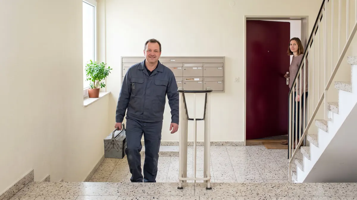 Fachkraft auf dem Weg in eine Wohnung im Mehrfamilienhaus